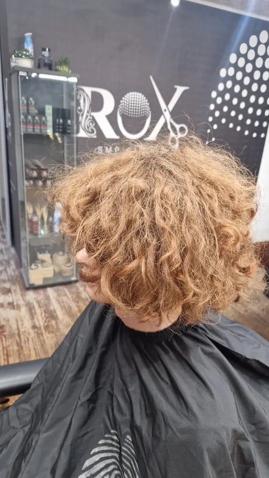 Long copper curls in front of the salon wall