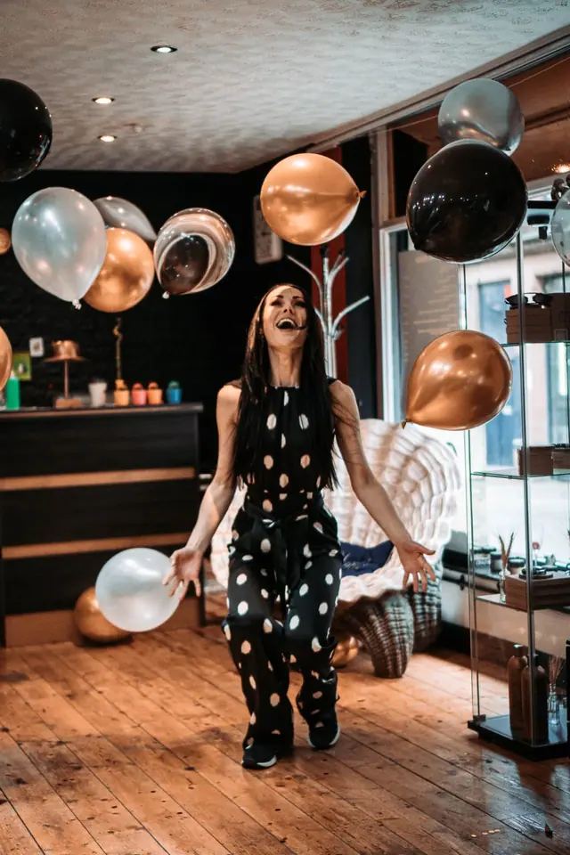 Roxy laughing among copper, black and silver balloons in the salon