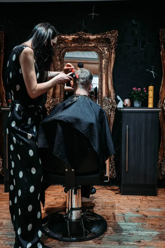 Roxy cutting a client’s hair in front of a gilded mirror