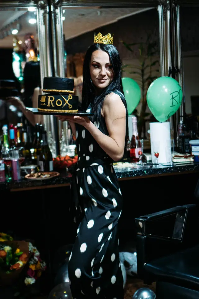Roxy holding a black and gold ROX cake